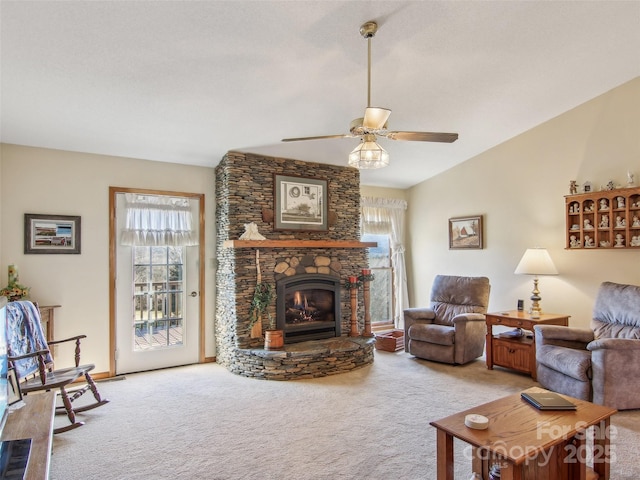 living room with ceiling fan, a stone fireplace, carpet, and lofted ceiling