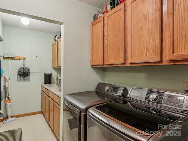 washroom with washing machine and clothes dryer, cabinets, and a textured ceiling