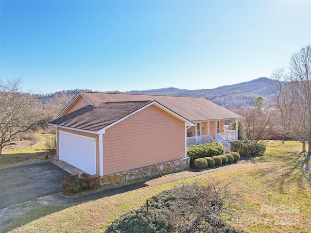 view of side of property with a mountain view, covered porch, a garage, and a yard