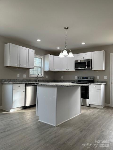 kitchen featuring pendant lighting, stainless steel appliances, light wood-style flooring, white cabinetry, and a kitchen island