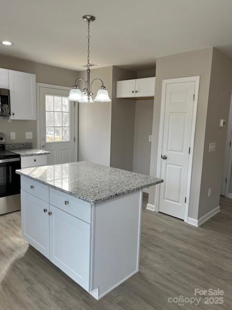 kitchen featuring light stone counters, a kitchen island, white cabinetry, stainless steel range with electric cooktop, and pendant lighting