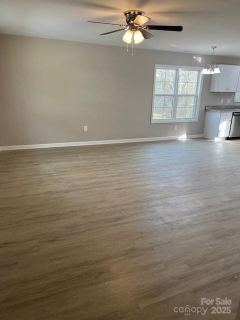 unfurnished living room featuring ceiling fan with notable chandelier, light wood finished floors, and baseboards