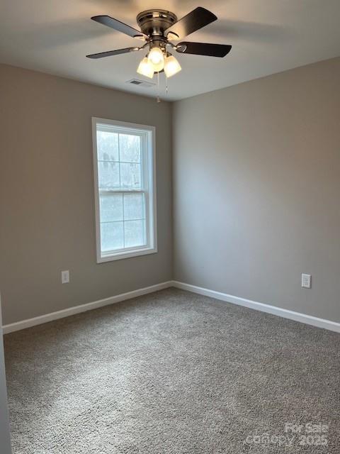 empty room featuring carpet, visible vents, baseboards, and ceiling fan