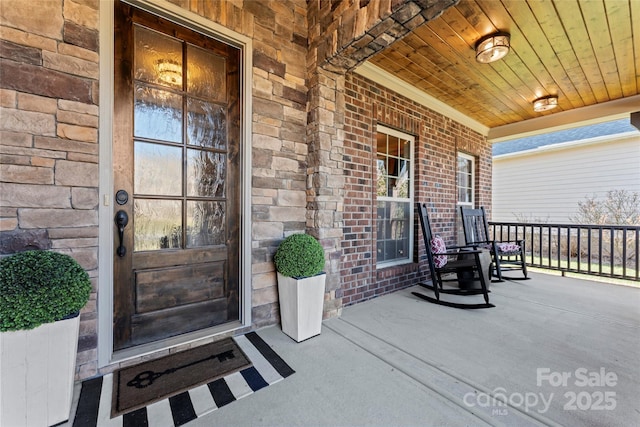 property entrance with a porch and brick siding