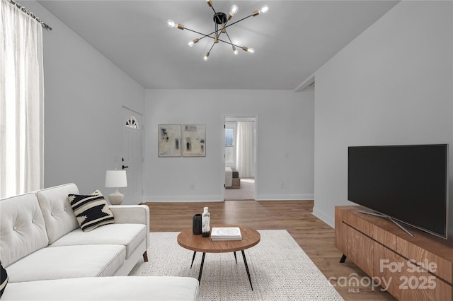 living area featuring light wood-type flooring, baseboards, and a notable chandelier