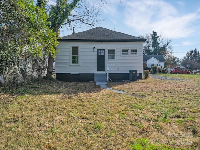 rear view of house featuring cooling unit, a lawn, roof with shingles, and entry steps
