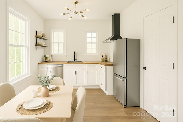 kitchen featuring appliances with stainless steel finishes, a sink, wood counters, light wood finished floors, and a chandelier