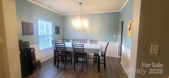 dining area featuring a wainscoted wall, dark wood-type flooring, crown molding, and a notable chandelier