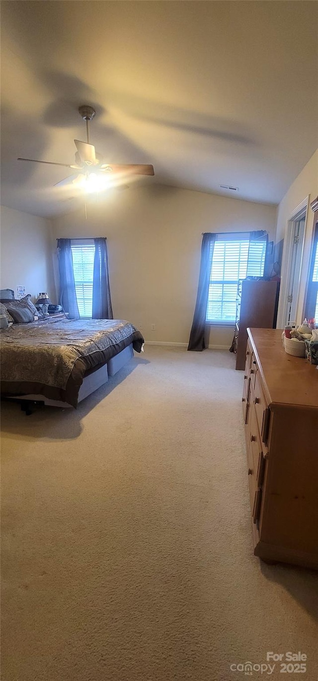 unfurnished bedroom featuring light carpet, multiple windows, visible vents, and lofted ceiling