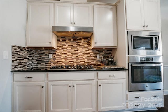 kitchen with appliances with stainless steel finishes, backsplash, white cabinets, and under cabinet range hood