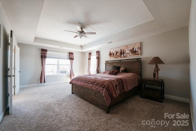 carpeted bedroom with a raised ceiling, ceiling fan, and baseboards