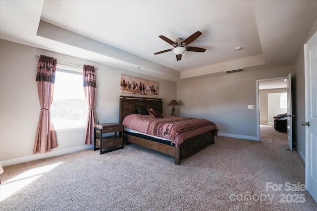 bedroom featuring carpet floors, a tray ceiling, visible vents, and baseboards