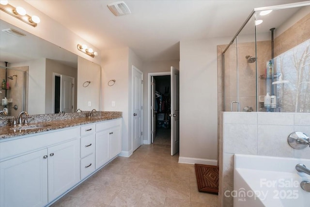 full bathroom with a sink, a shower stall, and double vanity