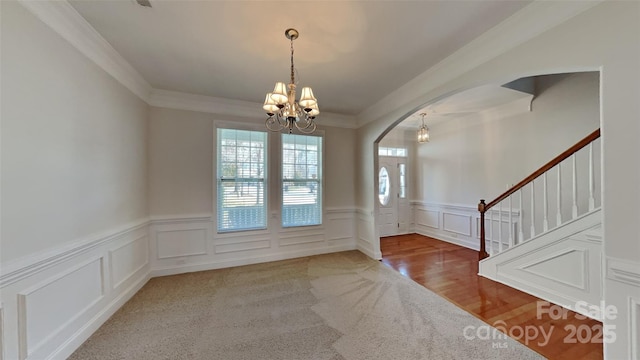 foyer entrance with crown molding and a chandelier