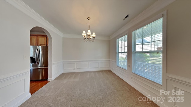 carpeted spare room featuring a chandelier and ornamental molding