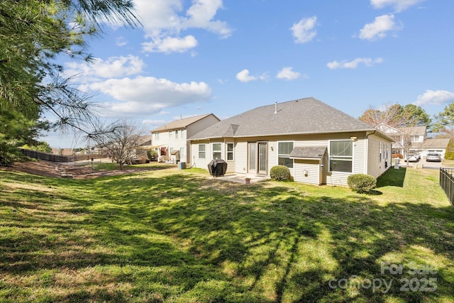 rear view of property featuring a patio, a lawn, and fence