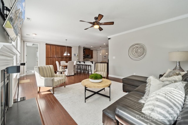 living area featuring baseboards, visible vents, dark wood-style floors, ornamental molding, and a fireplace