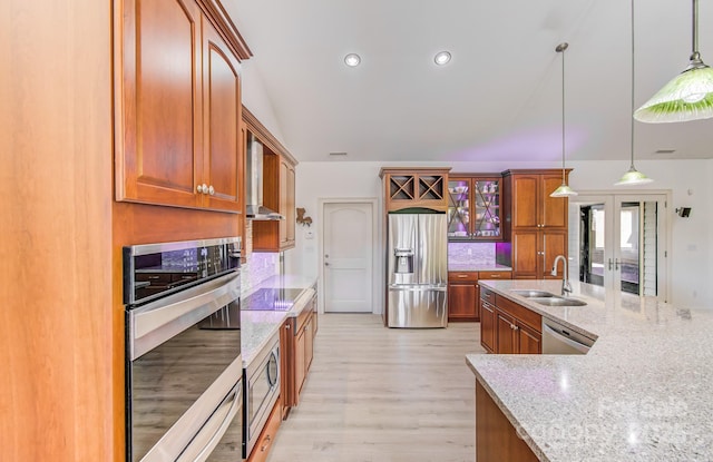 kitchen with appliances with stainless steel finishes, a sink, glass insert cabinets, and pendant lighting