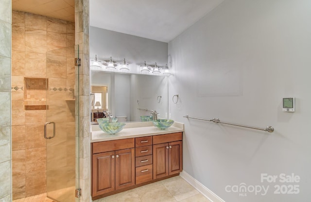 full bath with a stall shower, tile patterned flooring, vanity, and baseboards