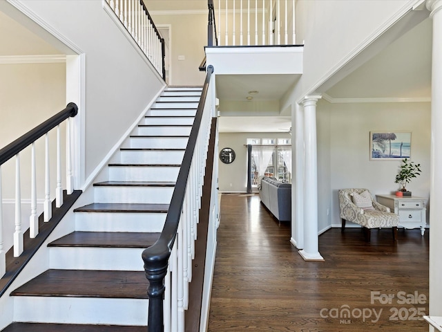 stairway with baseboards, ornamental molding, wood finished floors, and ornate columns