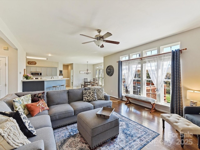 living area featuring ceiling fan, baseboards, and wood finished floors