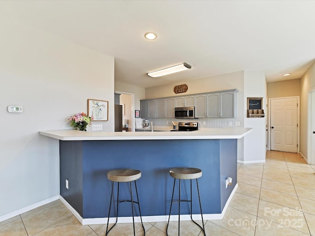 kitchen with light countertops, a breakfast bar area, a peninsula, and stainless steel appliances