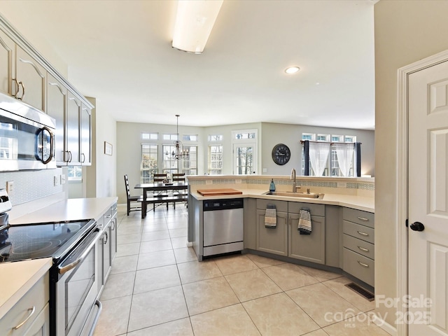 kitchen with gray cabinets, appliances with stainless steel finishes, light countertops, and a sink