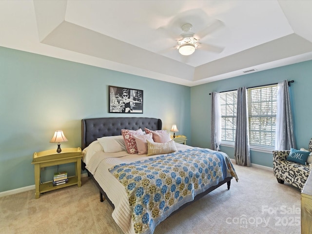 bedroom with ceiling fan, visible vents, baseboards, carpet, and a raised ceiling