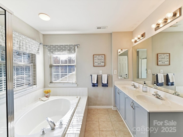 bathroom with a garden tub, tile patterned flooring, a sink, visible vents, and double vanity