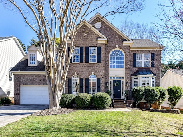 colonial home featuring a garage, driveway, a shingled roof, a front lawn, and brick siding