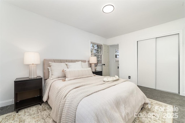 bedroom with a closet, light colored carpet, and baseboards