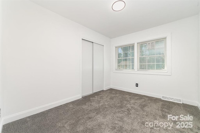 unfurnished bedroom featuring a closet, visible vents, baseboards, and carpet flooring