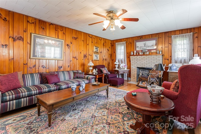 living area with a brick fireplace, wood finished floors, and a ceiling fan