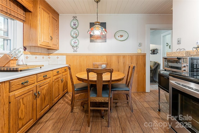 kitchen with electric stove, ornamental molding, light countertops, backsplash, and wood-type flooring