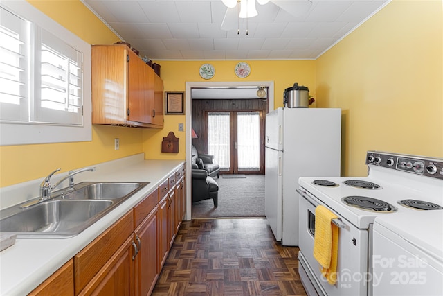 kitchen with white appliances, ceiling fan, brown cabinets, light countertops, and a sink