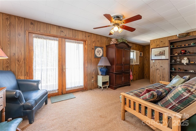 interior space featuring light carpet, plenty of natural light, wooden walls, and ceiling fan