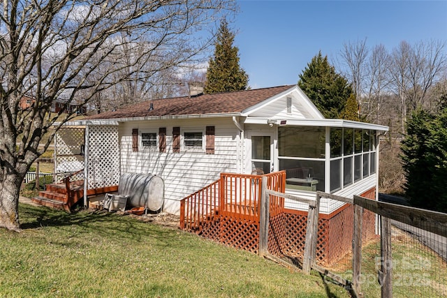 rear view of property with a sunroom, a yard, a deck, and fence