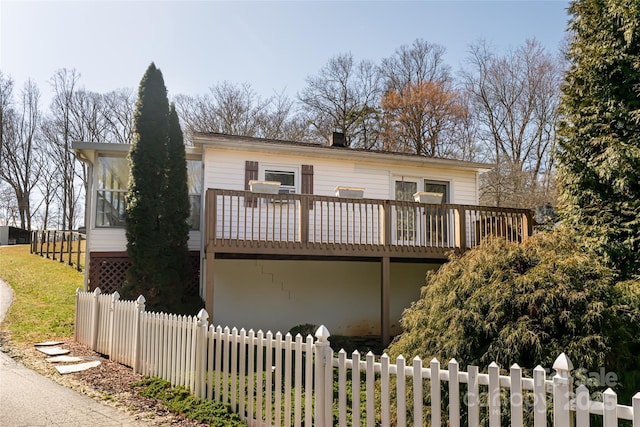 view of front of home featuring a sunroom, fence, and a wooden deck