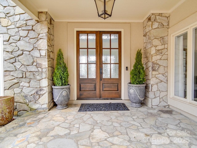 entrance to property with stone siding, french doors, and stucco siding