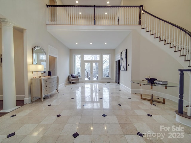 foyer entrance with french doors, a high ceiling, decorative columns, and baseboards