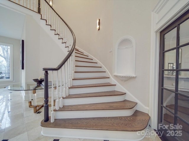 staircase featuring a high ceiling and tile patterned flooring