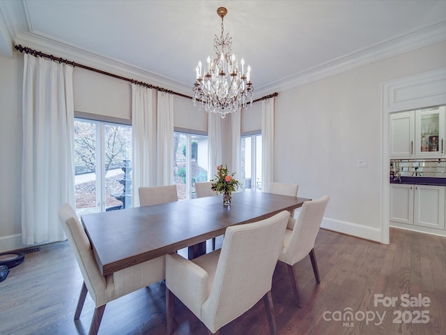 dining room featuring baseboards, a chandelier, wood finished floors, and crown molding