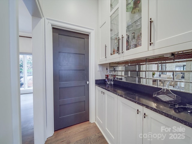 bar with a dry bar, decorative backsplash, and light wood-style floors