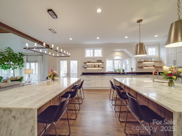 kitchen with open shelves, a breakfast bar area, dark stone countertops, and white cabinetry