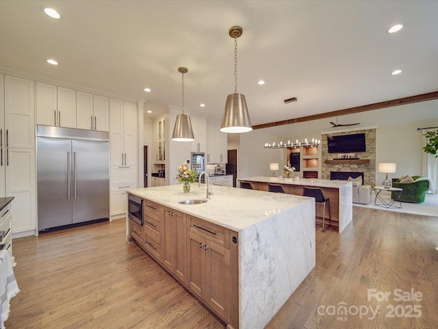 kitchen with light stone countertops, a spacious island, open floor plan, and built in appliances