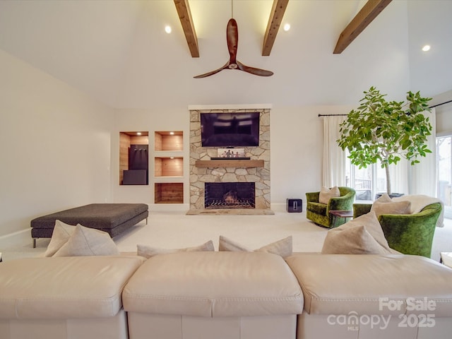 living area featuring carpet flooring, beamed ceiling, and a stone fireplace