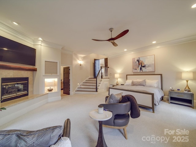 bedroom featuring light carpet, baseboards, a tile fireplace, ornamental molding, and recessed lighting