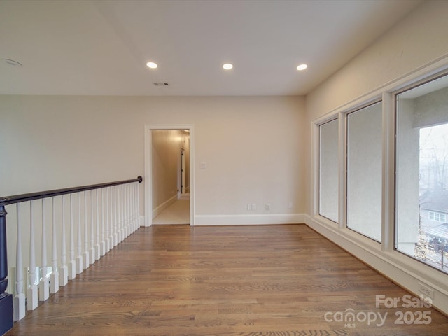 unfurnished room featuring baseboards, wood finished floors, visible vents, and recessed lighting