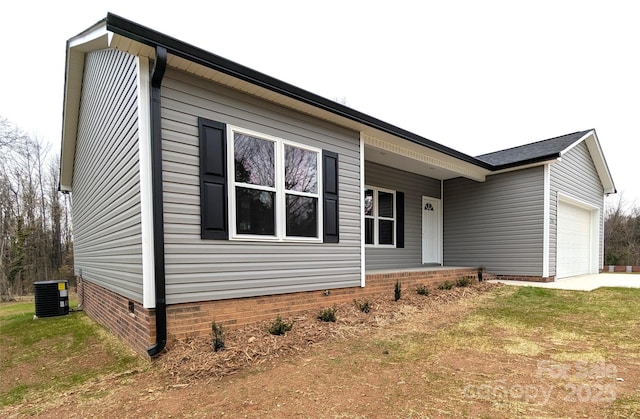 view of front of home with a front yard, central AC unit, and a garage