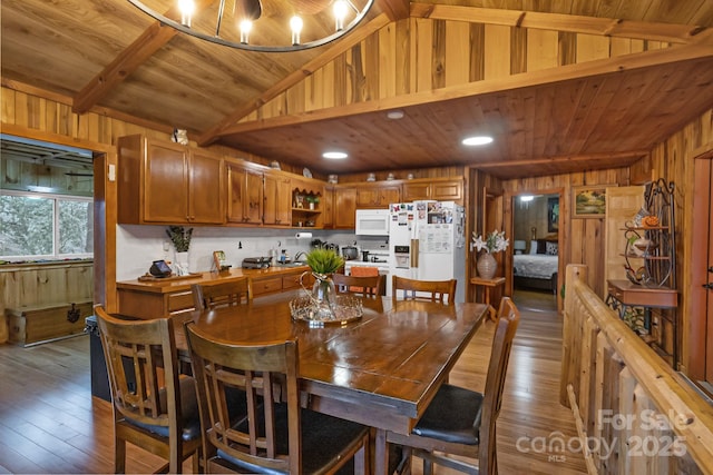 dining space with lofted ceiling with beams, hardwood / wood-style floors, wood walls, and wood ceiling